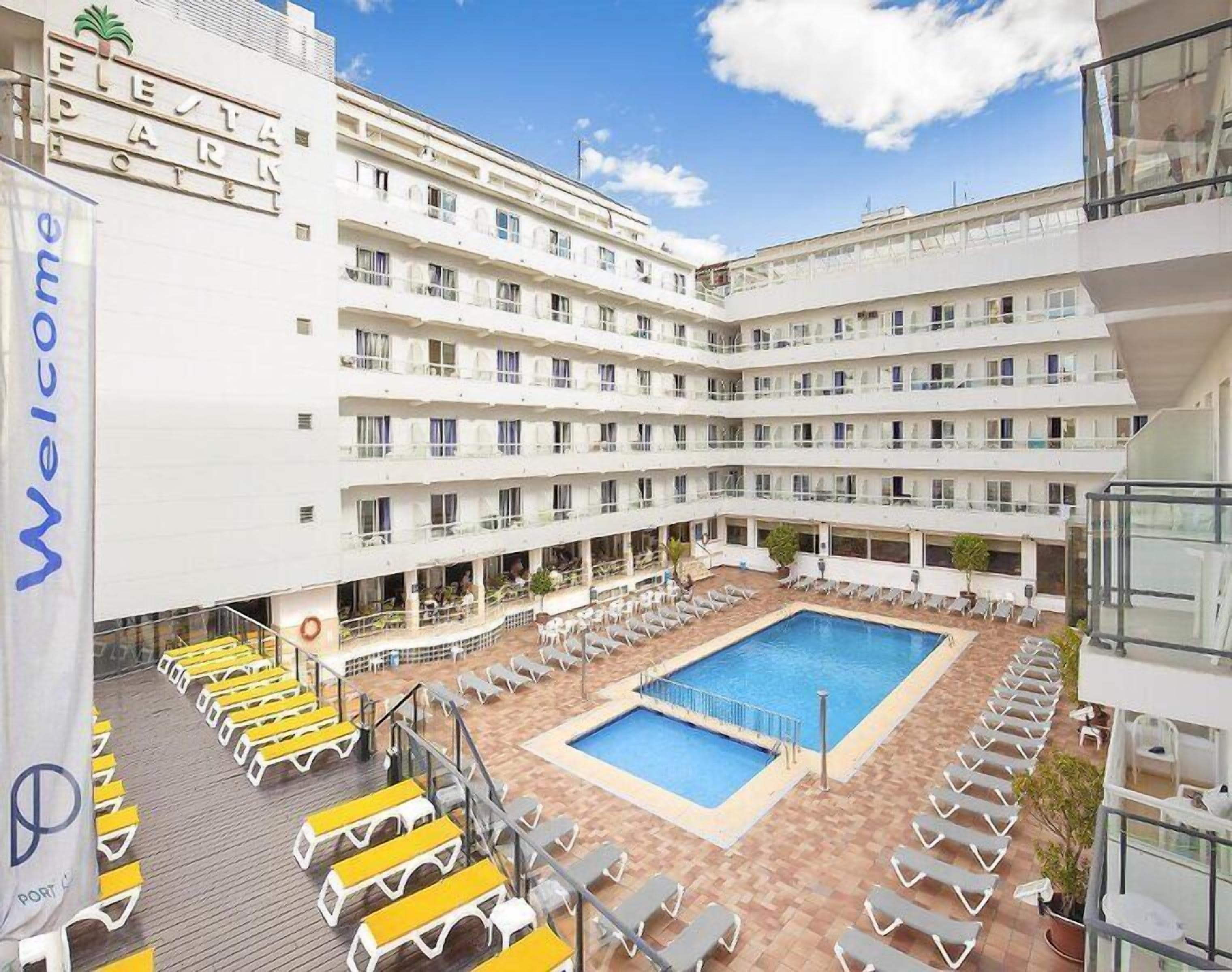 Un hotel de varios pisos, con un patio central que tiene una piscina y zonas de estar al aire libre.