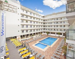 Un hotel de varios pisos, con un patio central que tiene una piscina y zonas de estar al aire libre.
