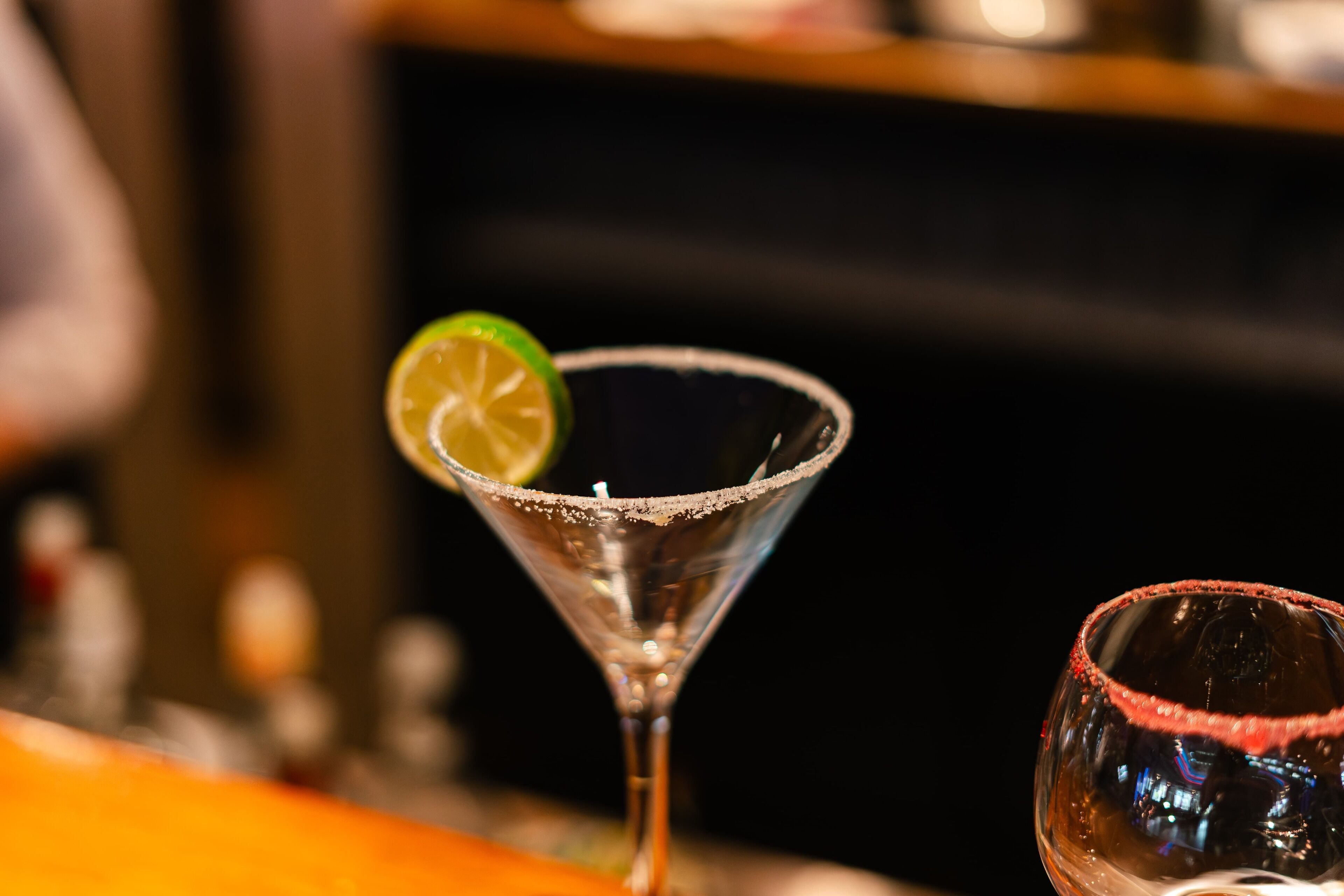 Una copa de martini con una cuña de lima sobre una barra.
