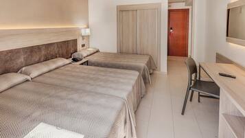 A hotel room with two beds, a desk, a chair, a TV, and a door.