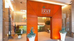 The entrance to Fiesta Park Hotel with a modern design, featuring a large potted plant and a sign above the door. - Port Fiesta Park Hotel (Benidorm)
