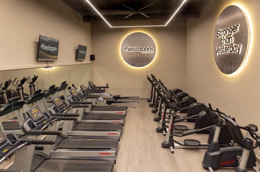 Een sportschool met loopbanden en elliptische trainers, een spiegel en motiverende muurdecoratie.