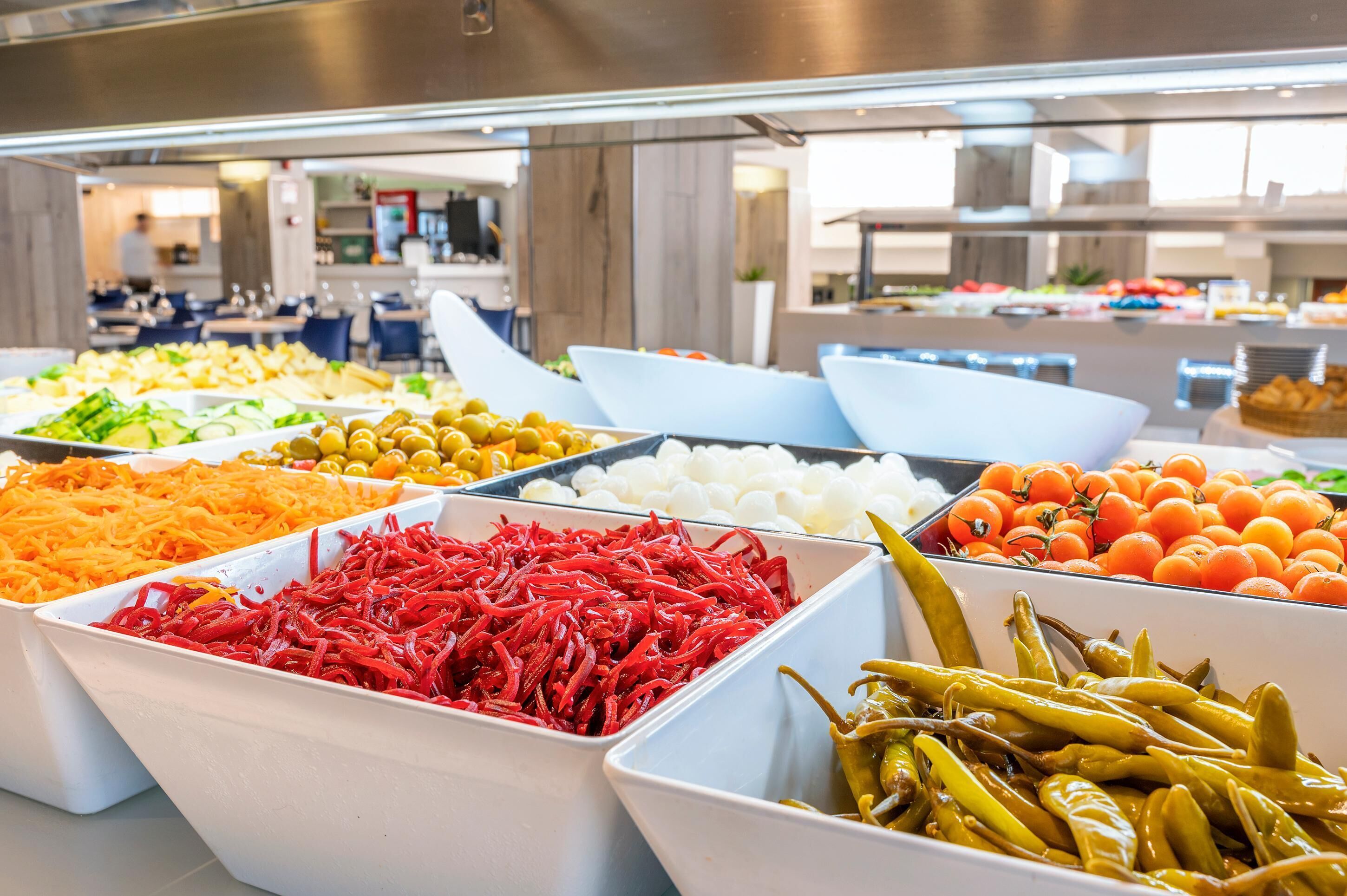 A buffet with various food items including vegetables and fruits.