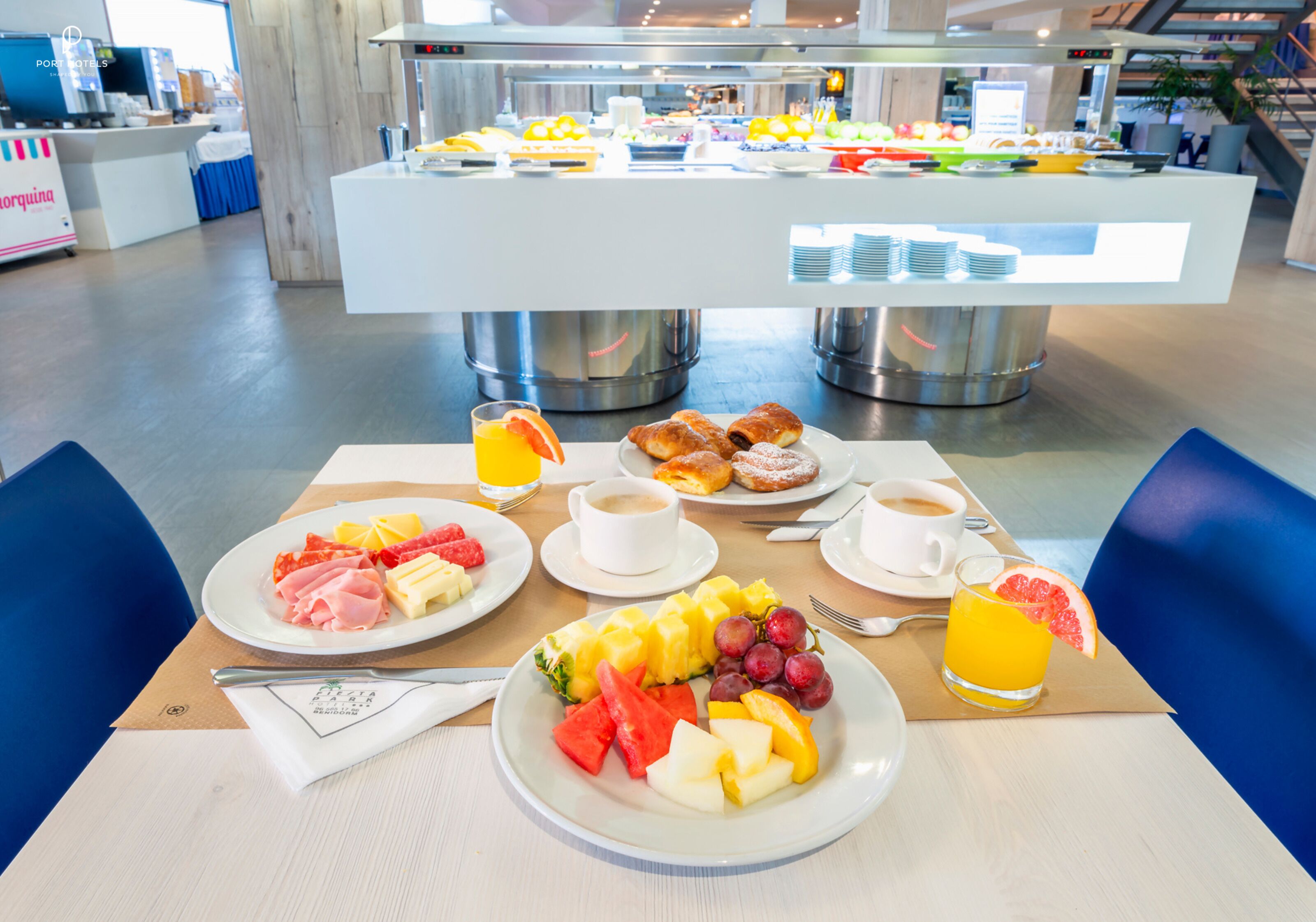 A breakfast buffet with various fruits, pastries, and beverages.
