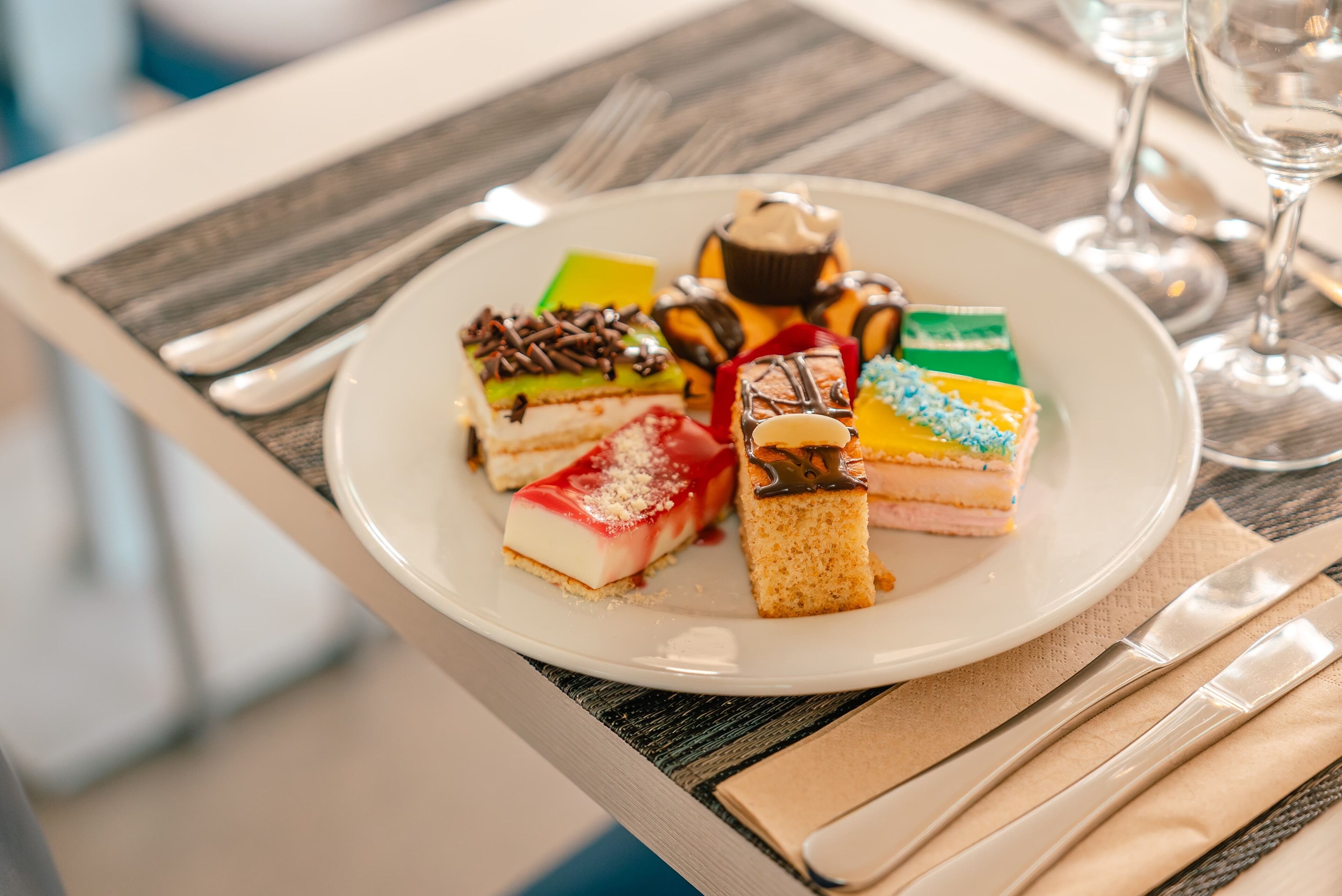 A plate of assorted desserts on a table with a napkin and cutlery.