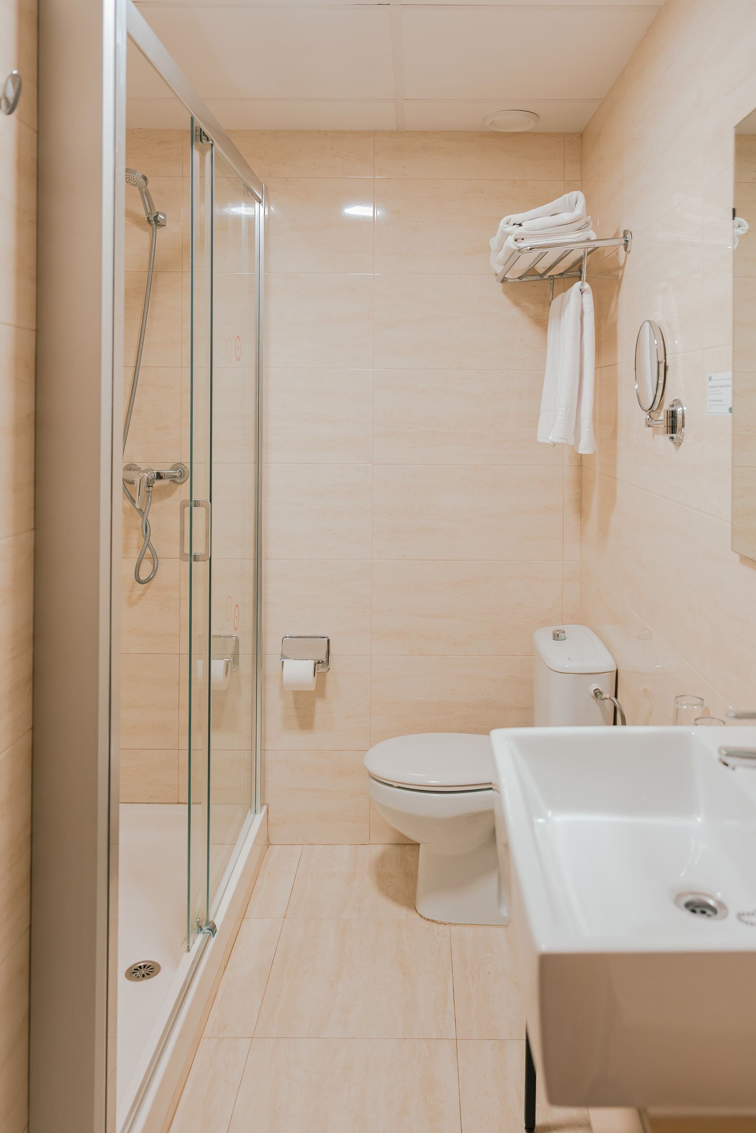 A modern bathroom with a glass-enclosed shower, a toilet, and a sink.