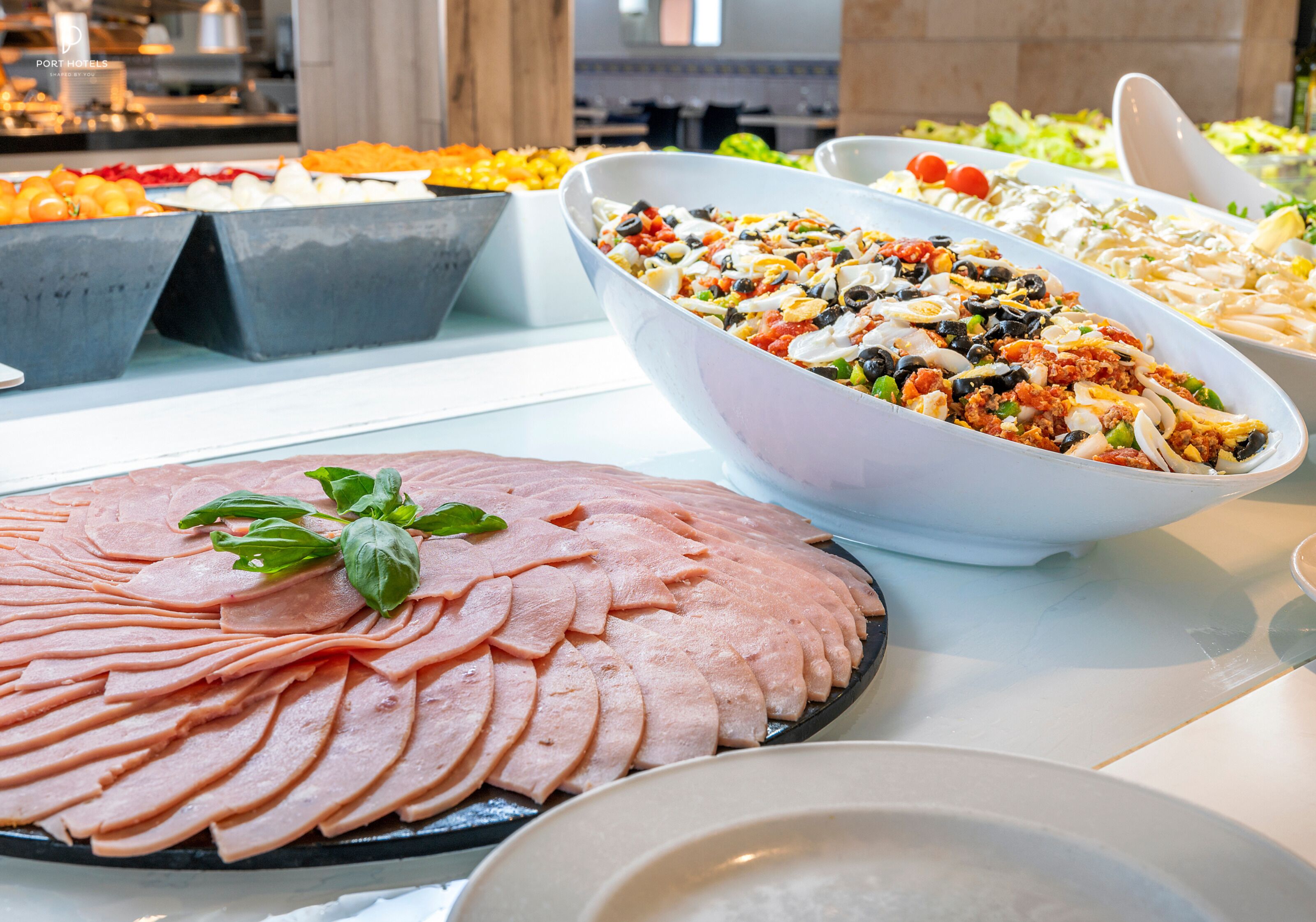 A buffet with various dishes including sliced ham, salads, and other prepared foods.