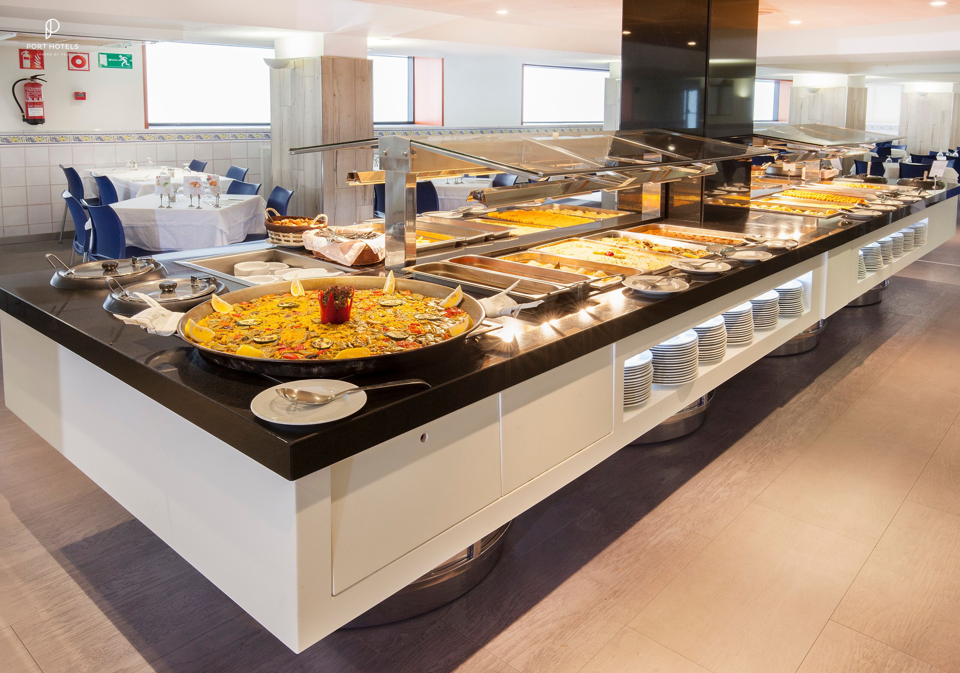 Ein Buffet mit mehreren Servierstationen, einer zentralen Insel mit einer großen Schale und einer Sitzgelegenheit mit Tischen und Stühlen.