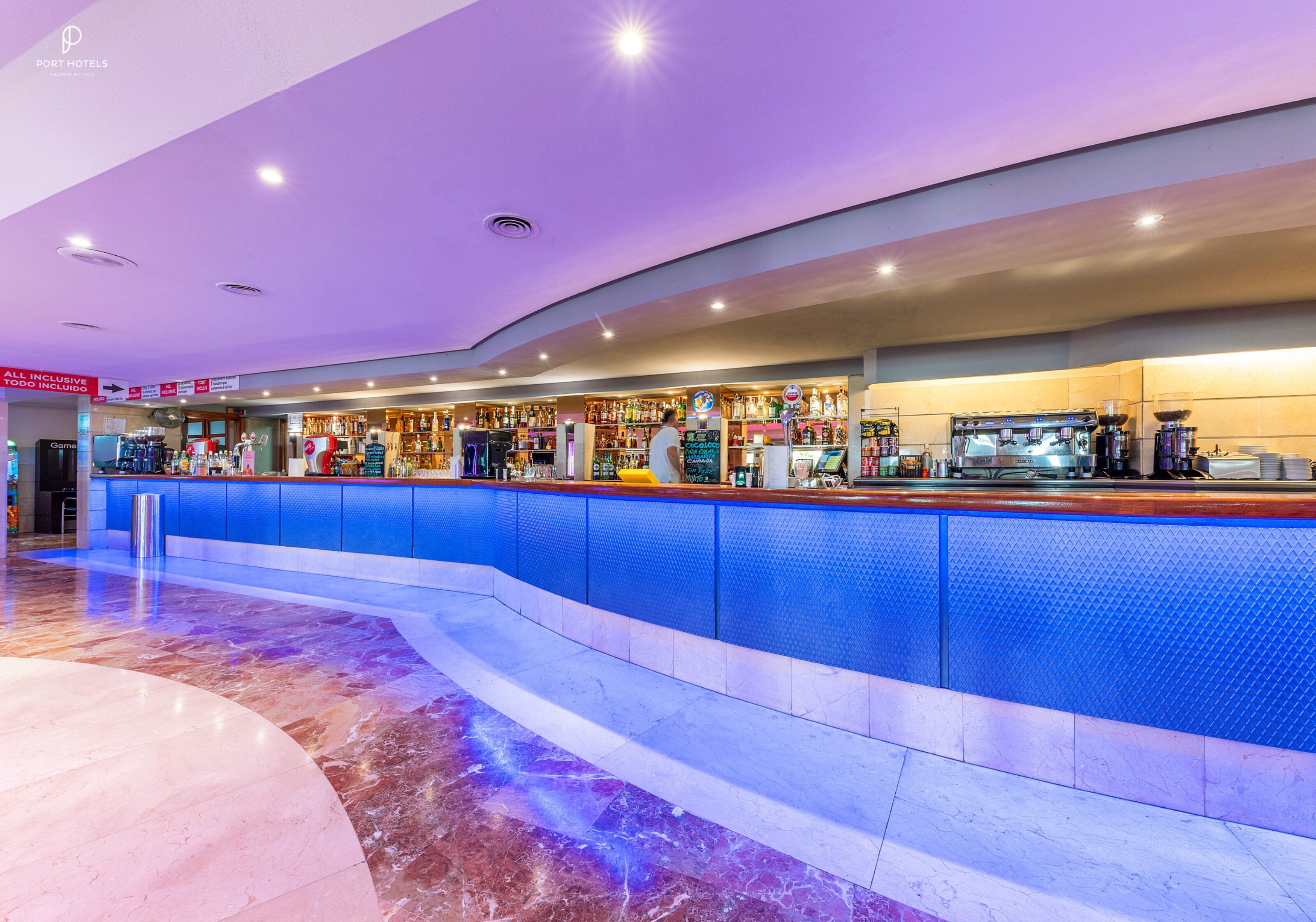A modern bar area with a blue counter and a variety of beverages.