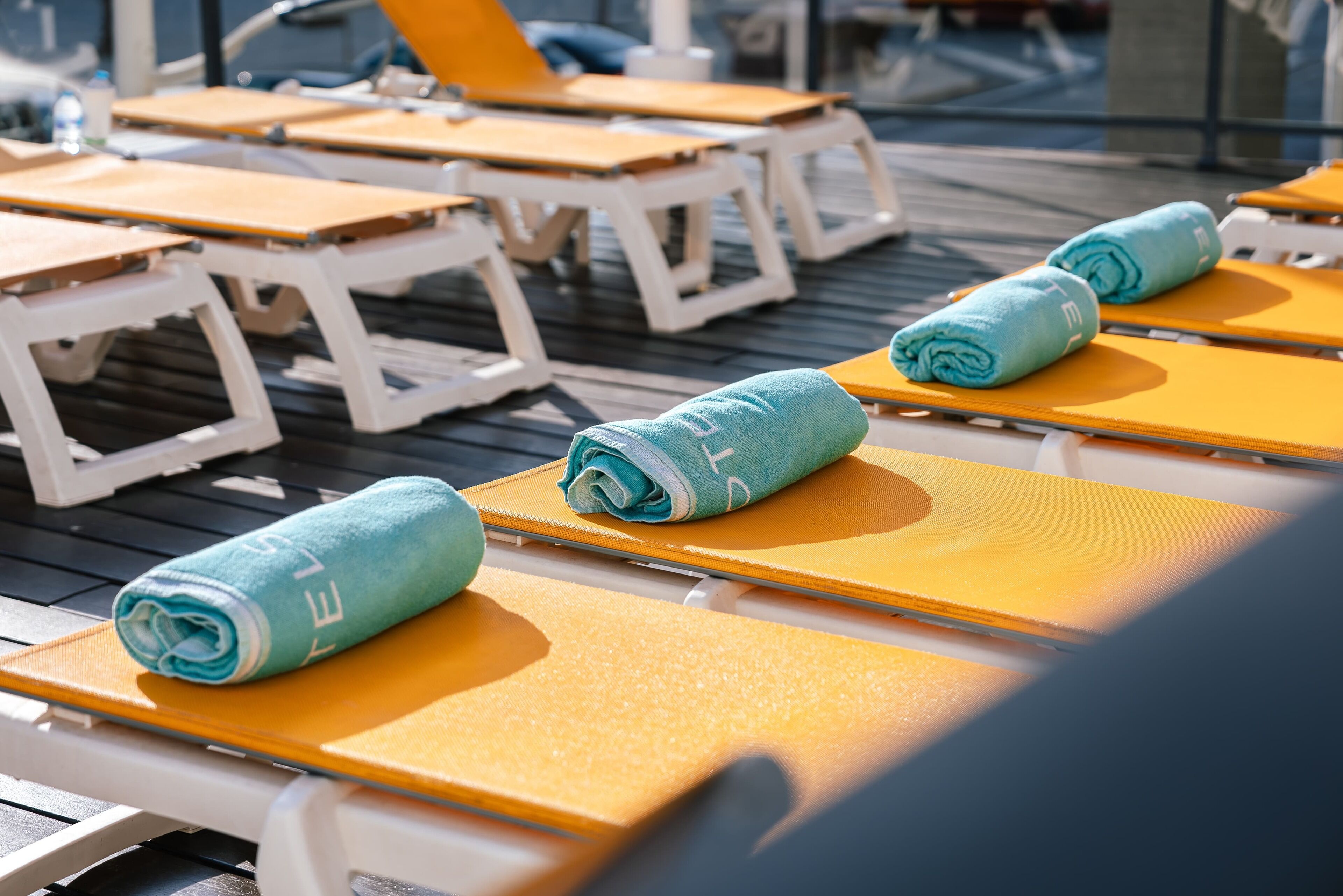 Sun loungers with towels, arranged on a wooden deck.