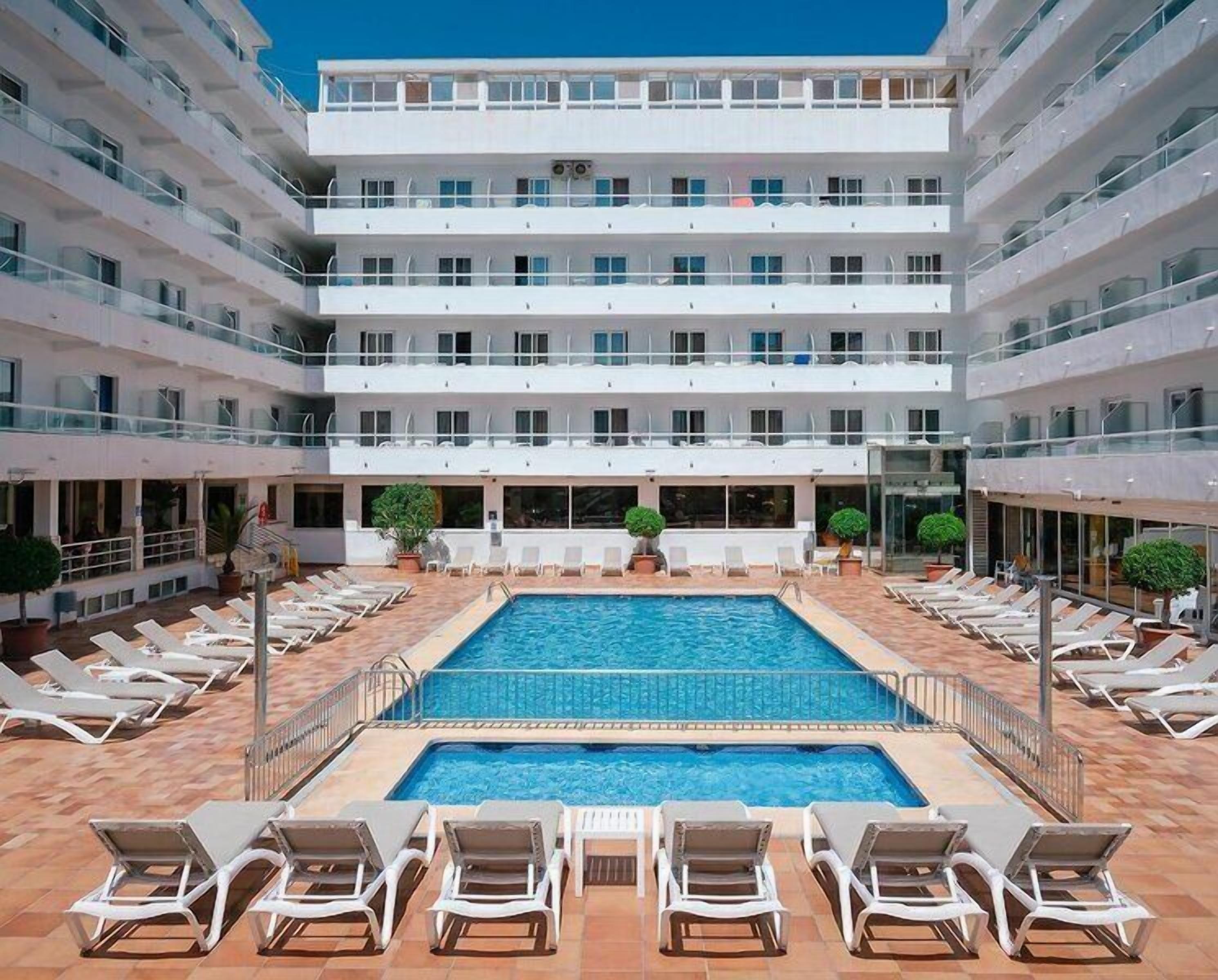 Hotel amb piscina central, múltiples balcons i gandules.