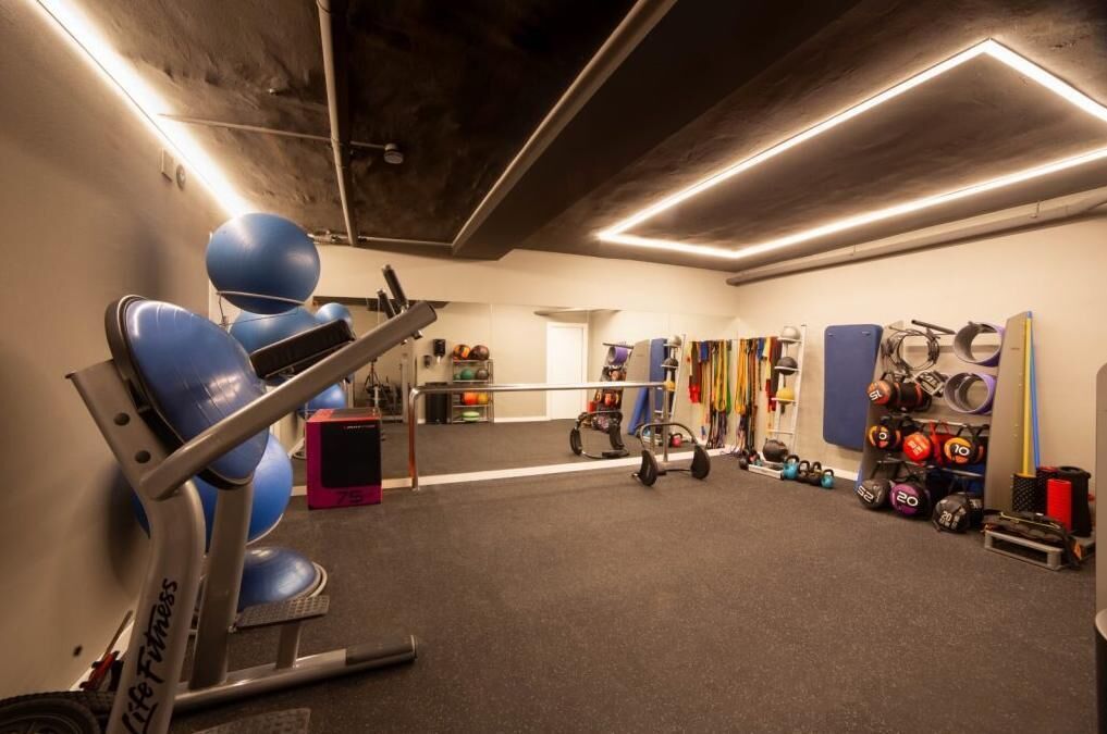 Un gimnasio con equipamiento de ejercicio, una cinta de correr y elementos para levantamiento de pesas.