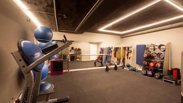 Un gimnasio con equipamiento de ejercicio, una cinta de correr y elementos para levantamiento de pesas.