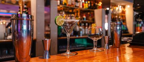 A bar area with various cocktail shakers and glasses on a wooden counter.