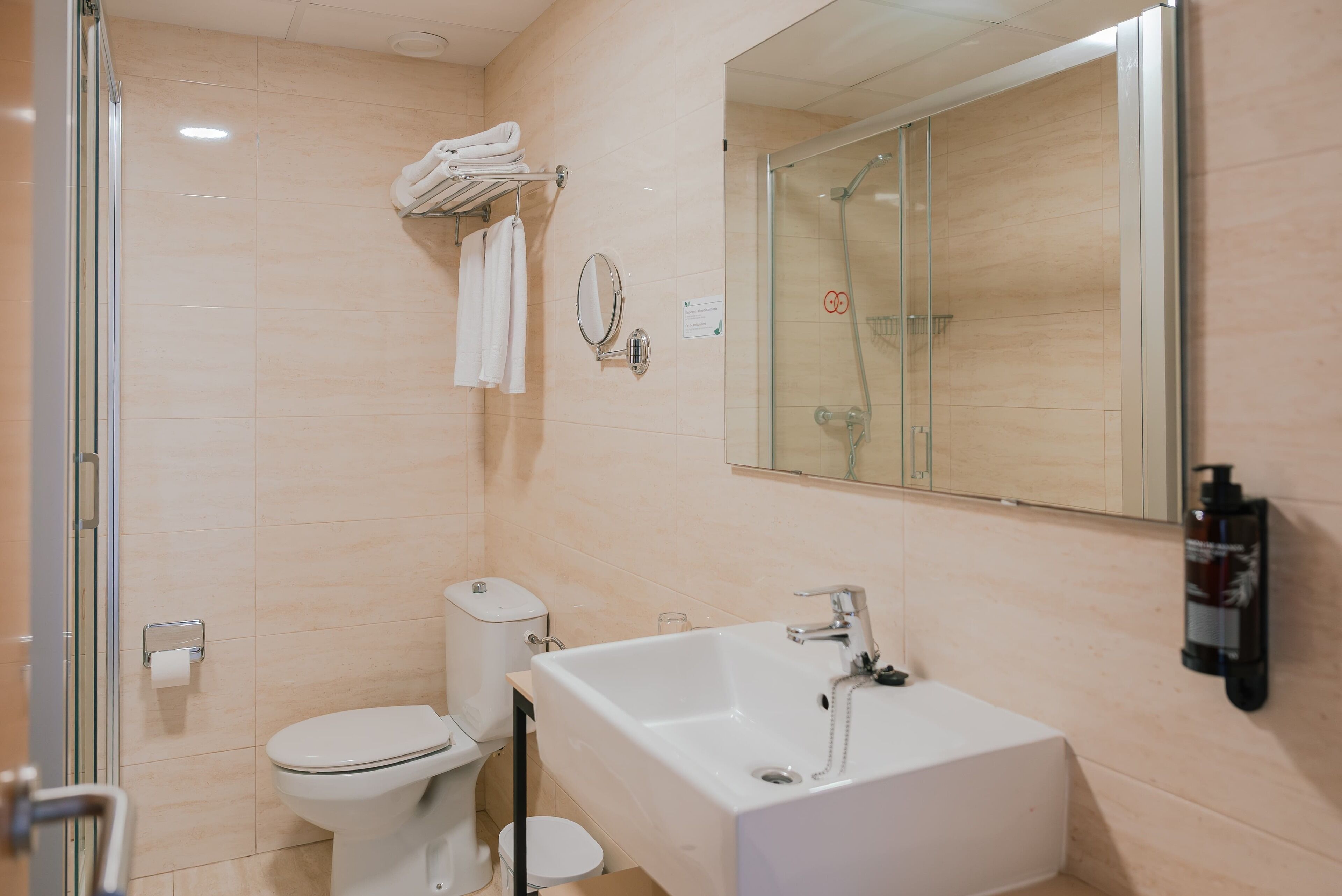 Et moderne badeværelse med toilet, vask og brusekabine med glasvægge.
