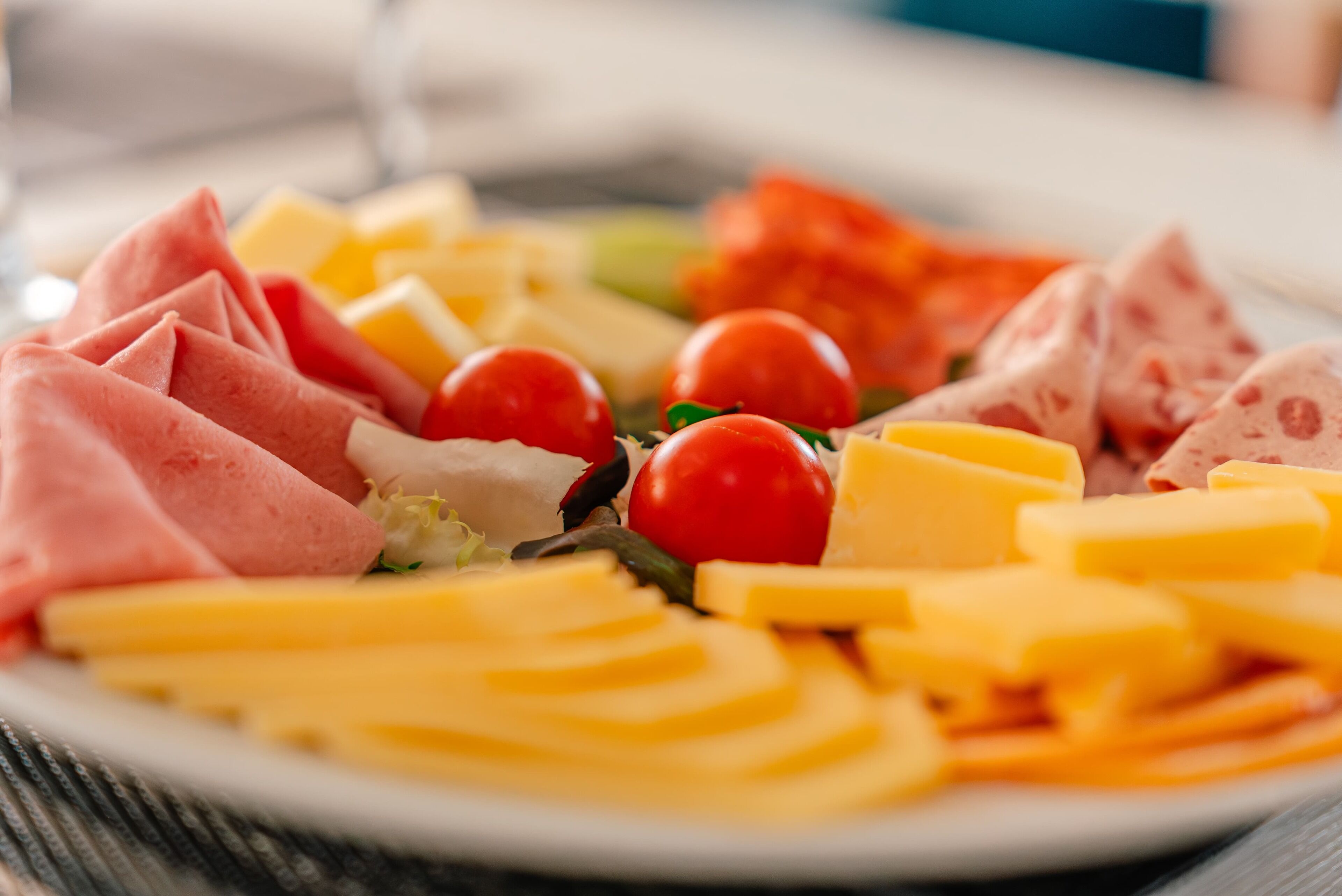 Un plato con quesos variados, embutidos y tomates cherry.