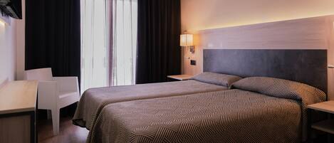 A hotel room with a bed, a desk, and a chair.