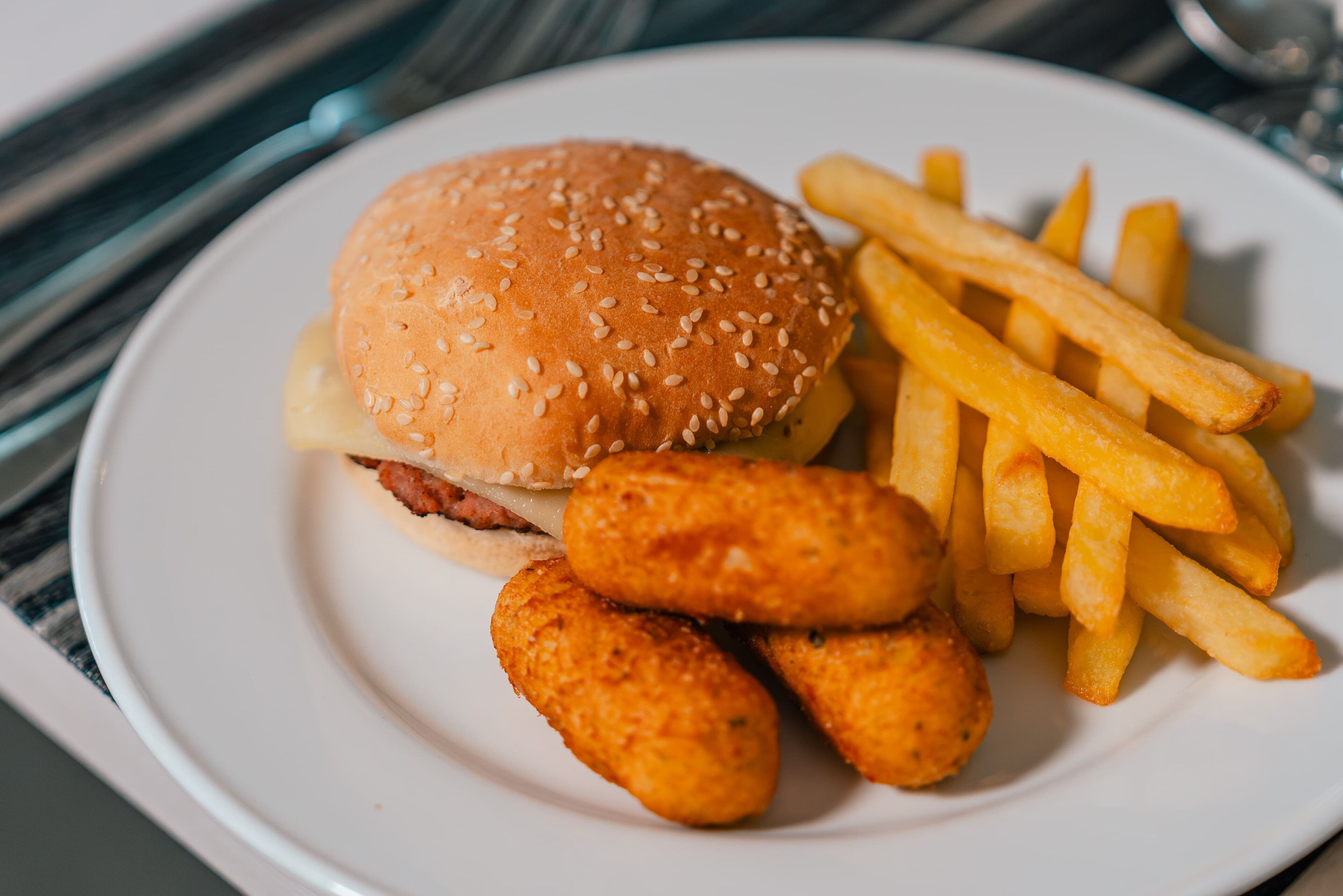 A plate with a hamburger, French fries, and chicken nuggets.