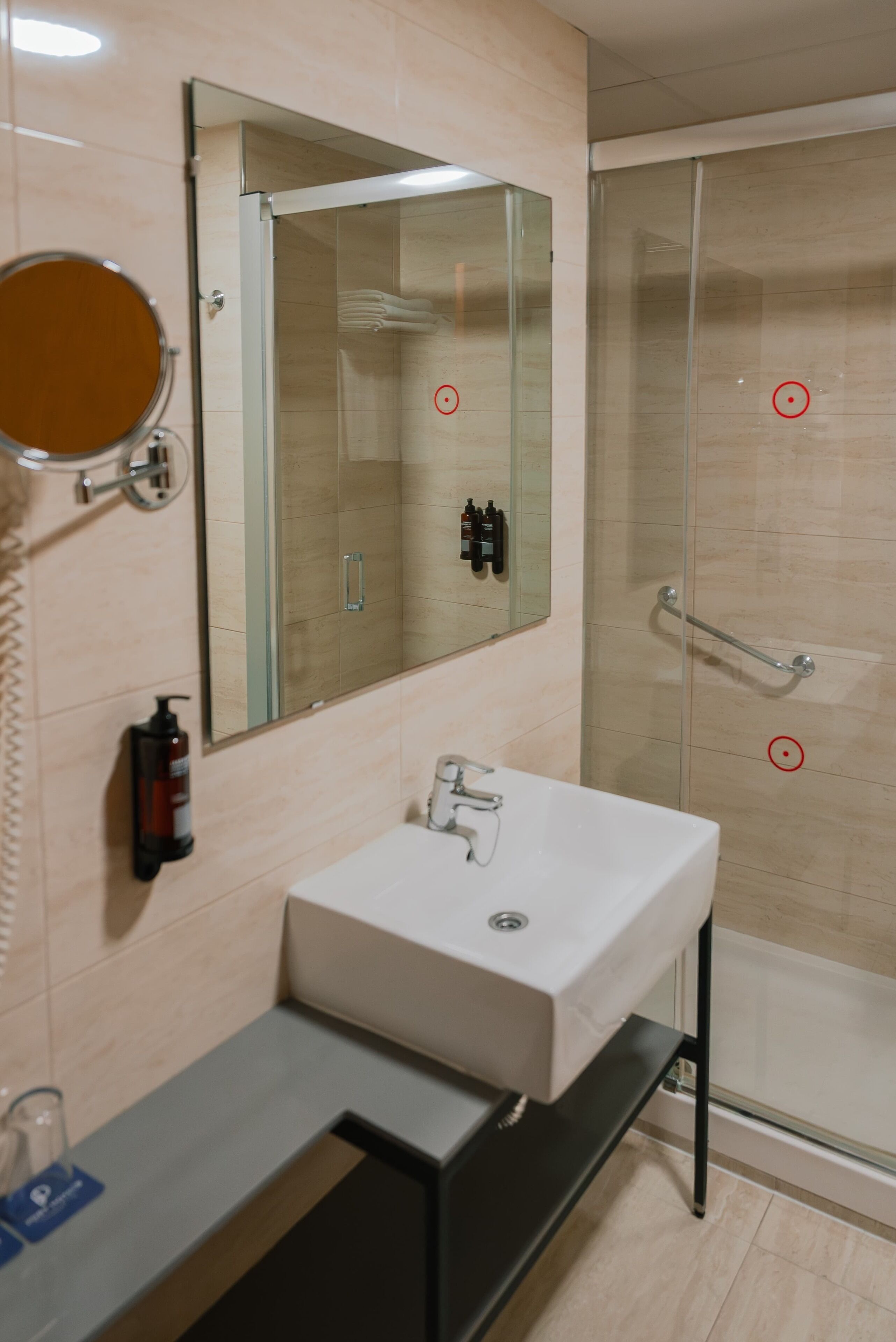 A modern bathroom with a large mirror, a white sink, and a glass shower enclosure.
