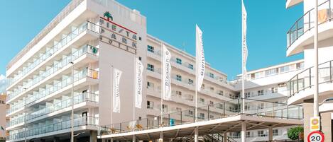 A multi-story hotel with a modern design, featuring balconies and a covered entrance area.