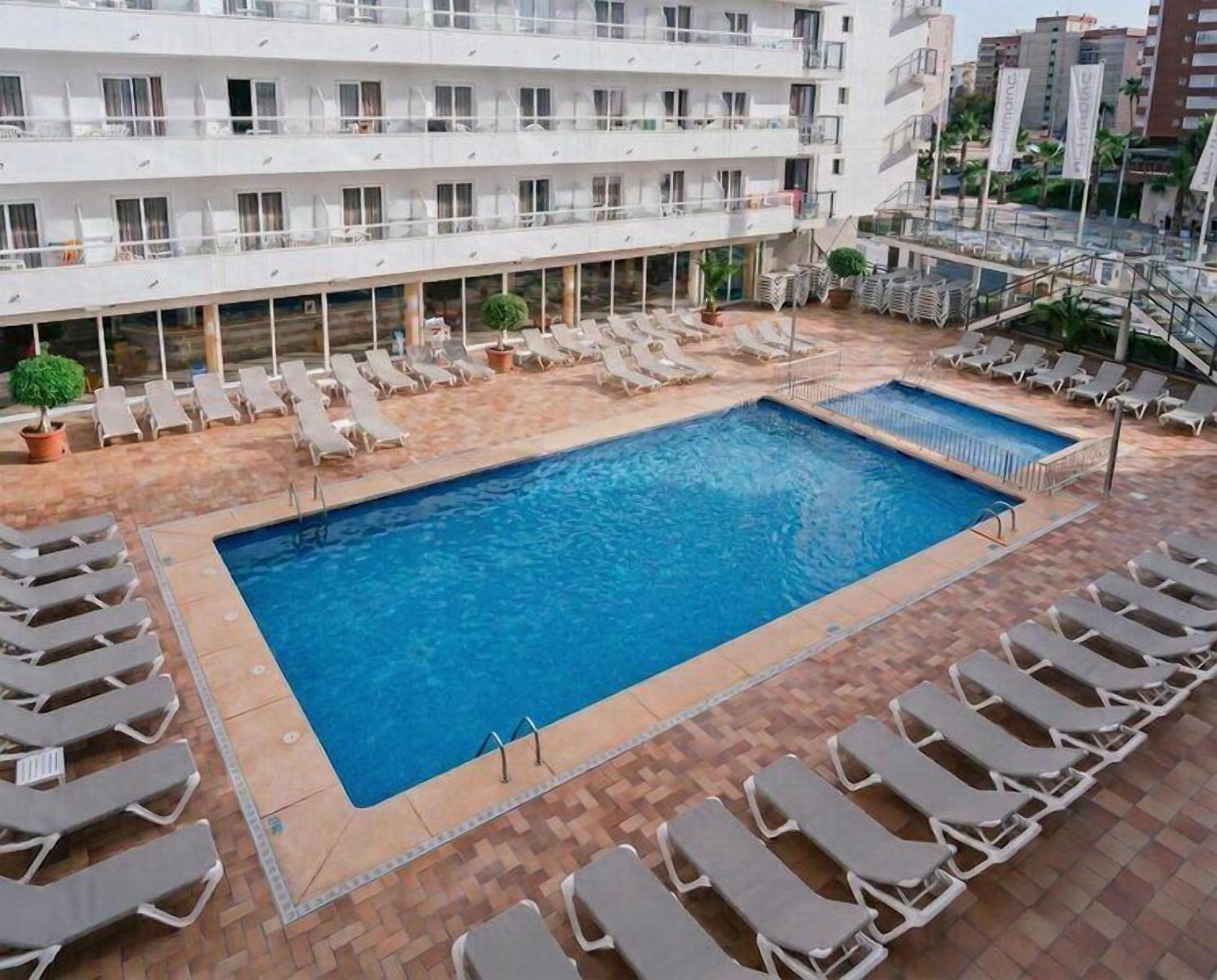 A hotel pool area with multiple lounge chairs and a large swimming pool.