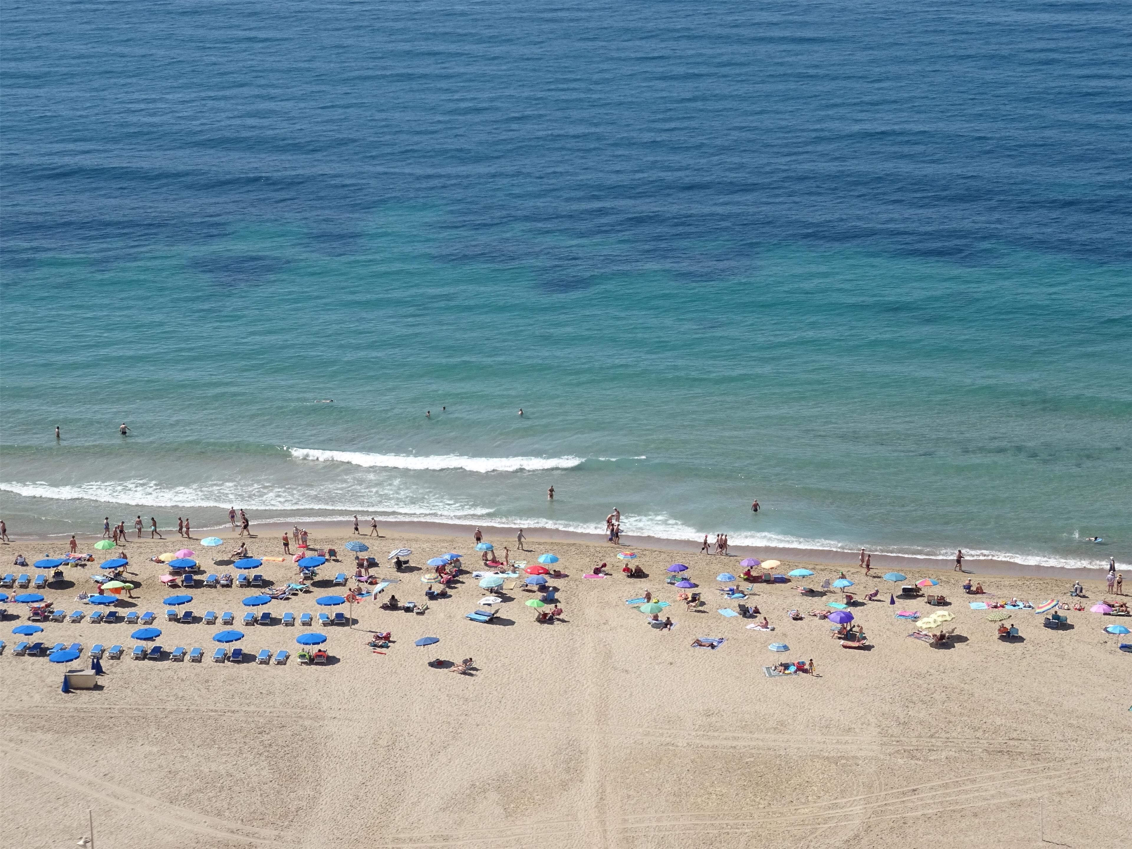 A beach with numerous umbrellas and sun loungers, indicating a beach resort setting.