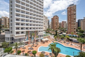 A hotel with multiple floors, a swimming pool, and a landscaped area with palm trees and lounge chairs. - Poseidon Resort (Benidorm)