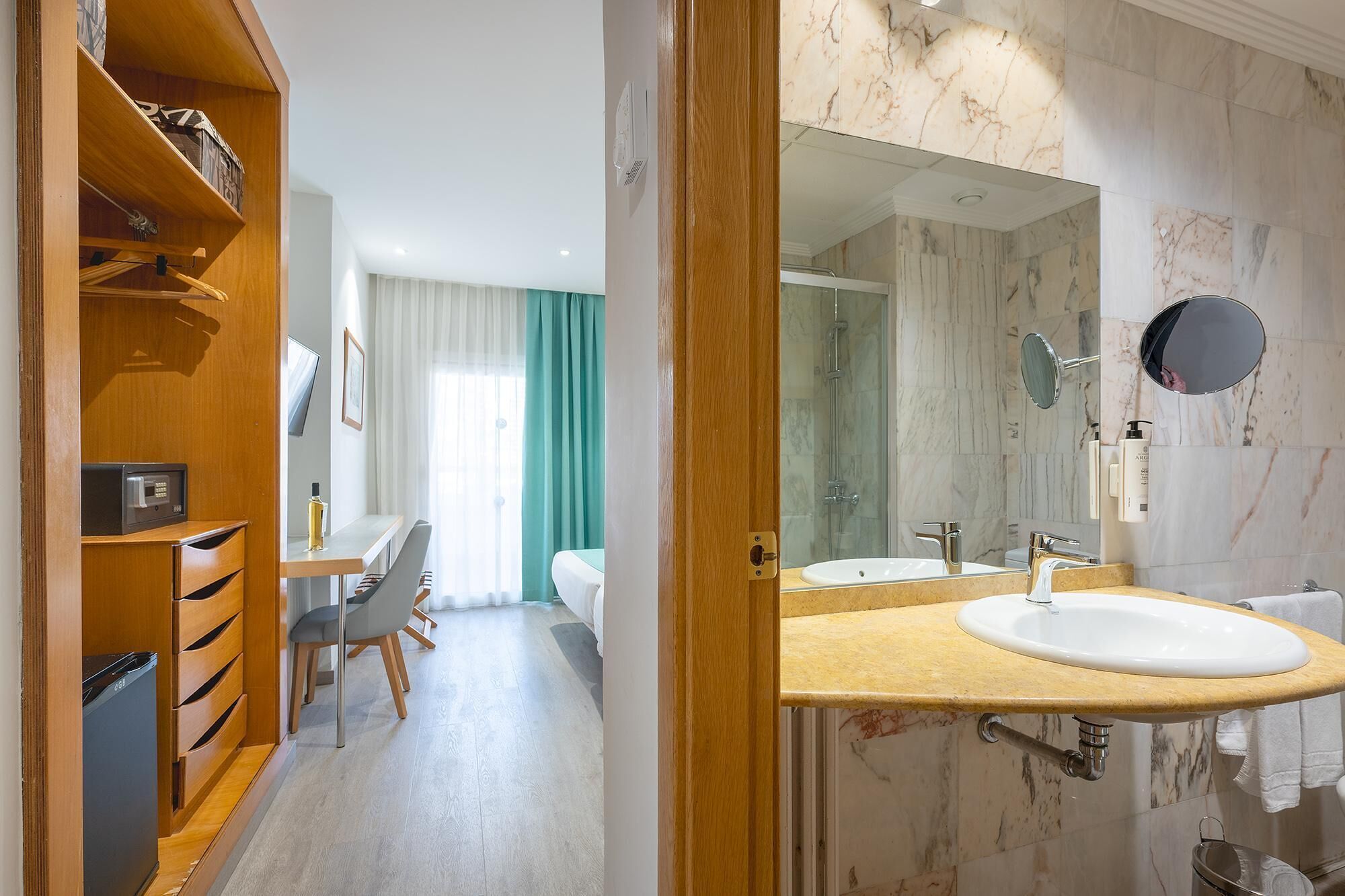 Un baño de hotel con tocador de mármol, un espejo grande y zona de ducha.