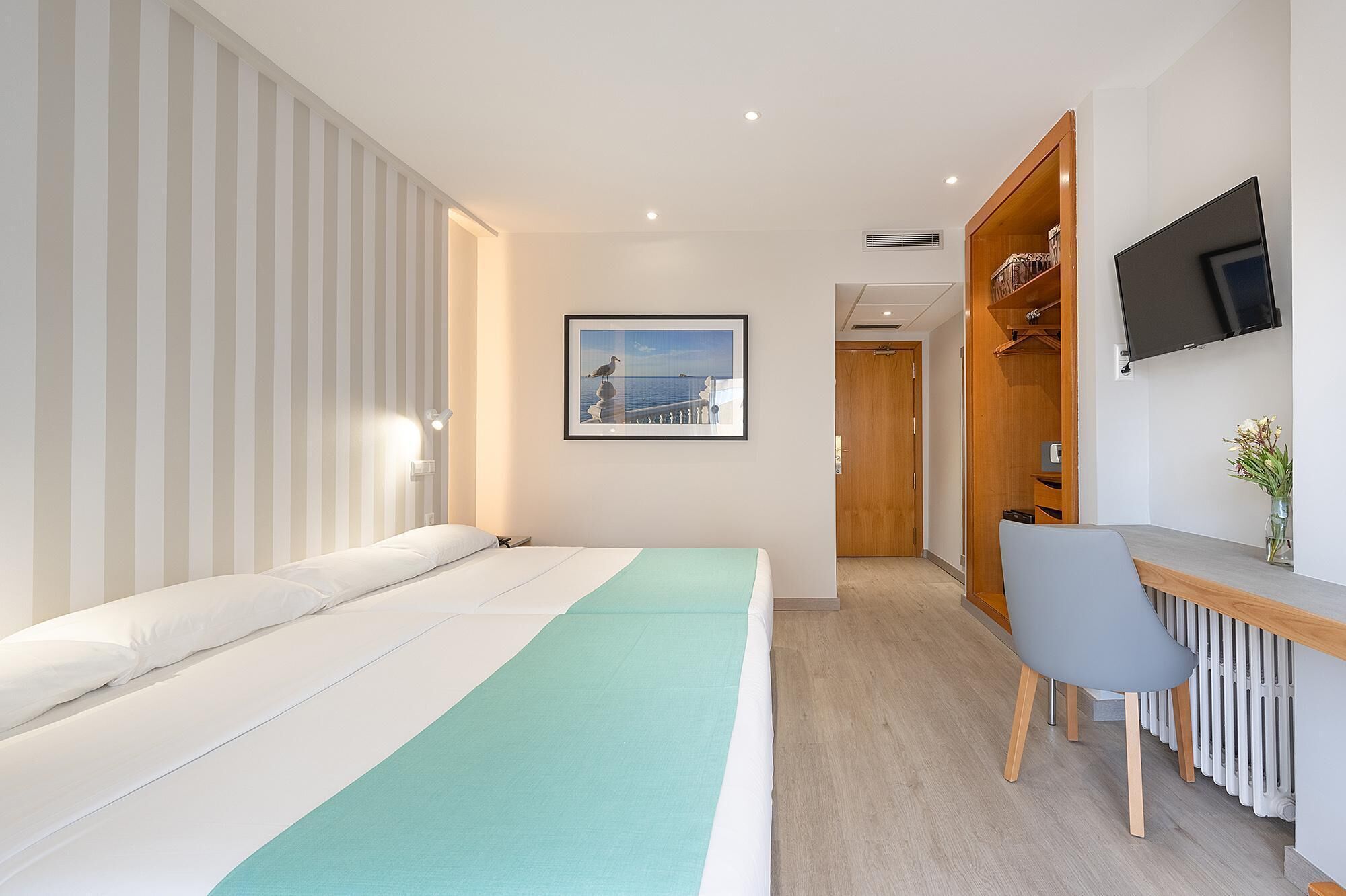 Une chambre d’hôtel moderne équipée d’un lit, d’un bureau et d’une télévision.