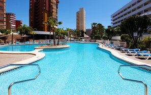 A swimming pool with lounge chairs and palm trees, surrounded by tall buildings. - Poseidon Resort (Benidorm)