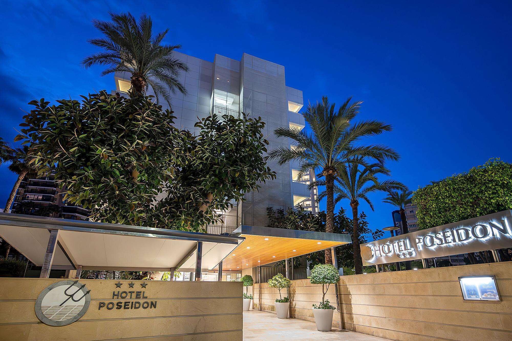 A modern hotel with a prominent sign, palm trees, and a covered walkway.