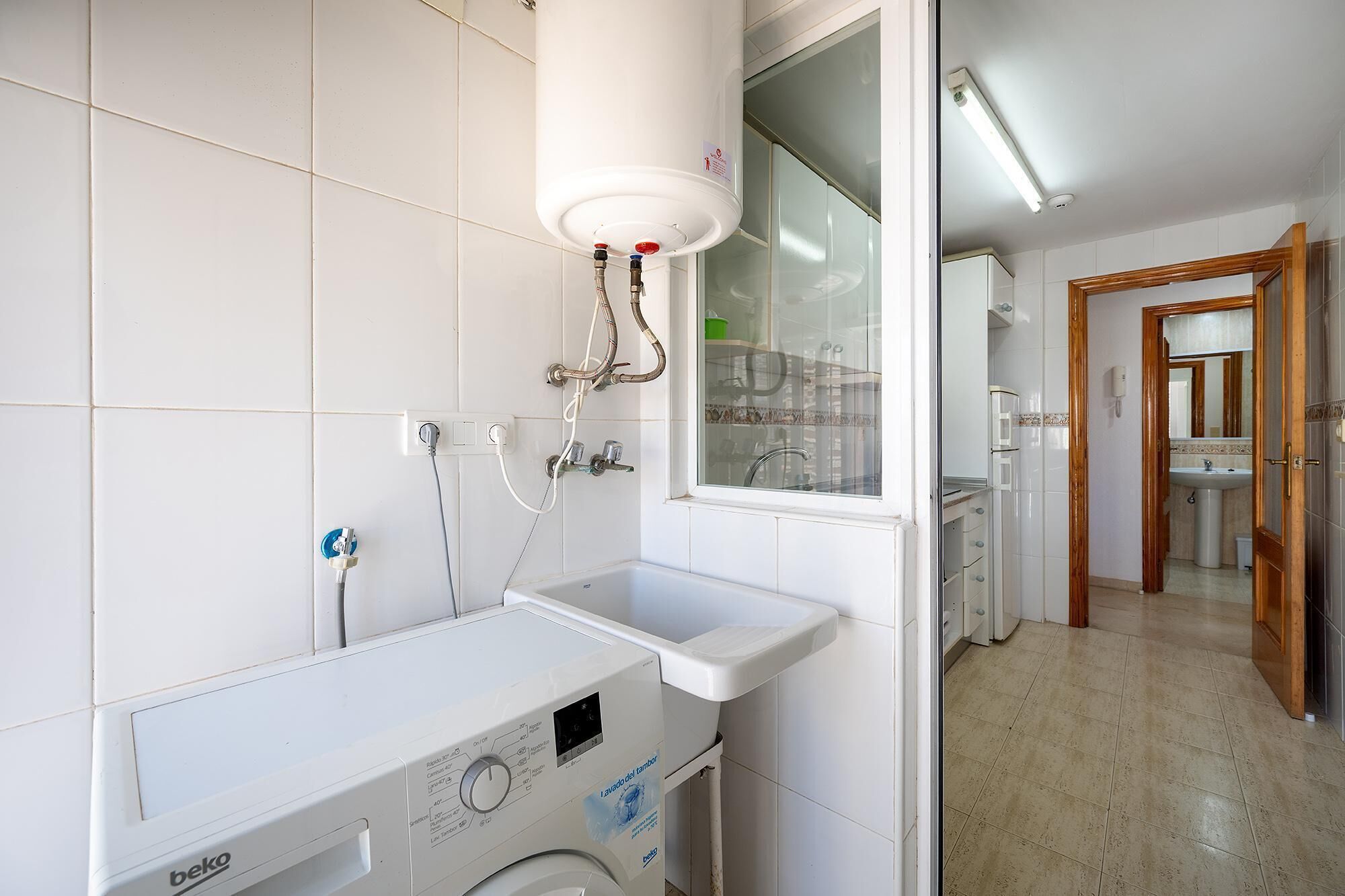 Un baño con lavadora, lavamanos y ducha.