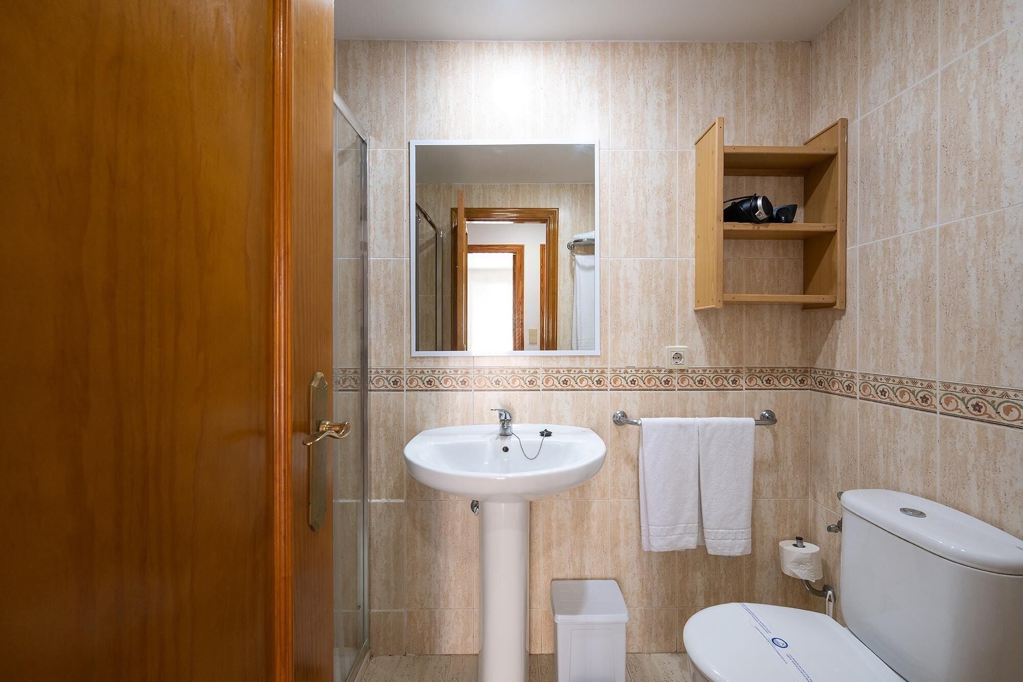 A bathroom with a sink, toilet, and a mirror.