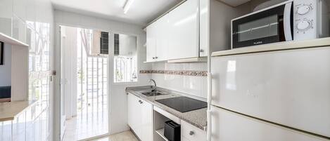 A modern kitchen with white cabinets, a built-in microwave, and a stainless steel sink.