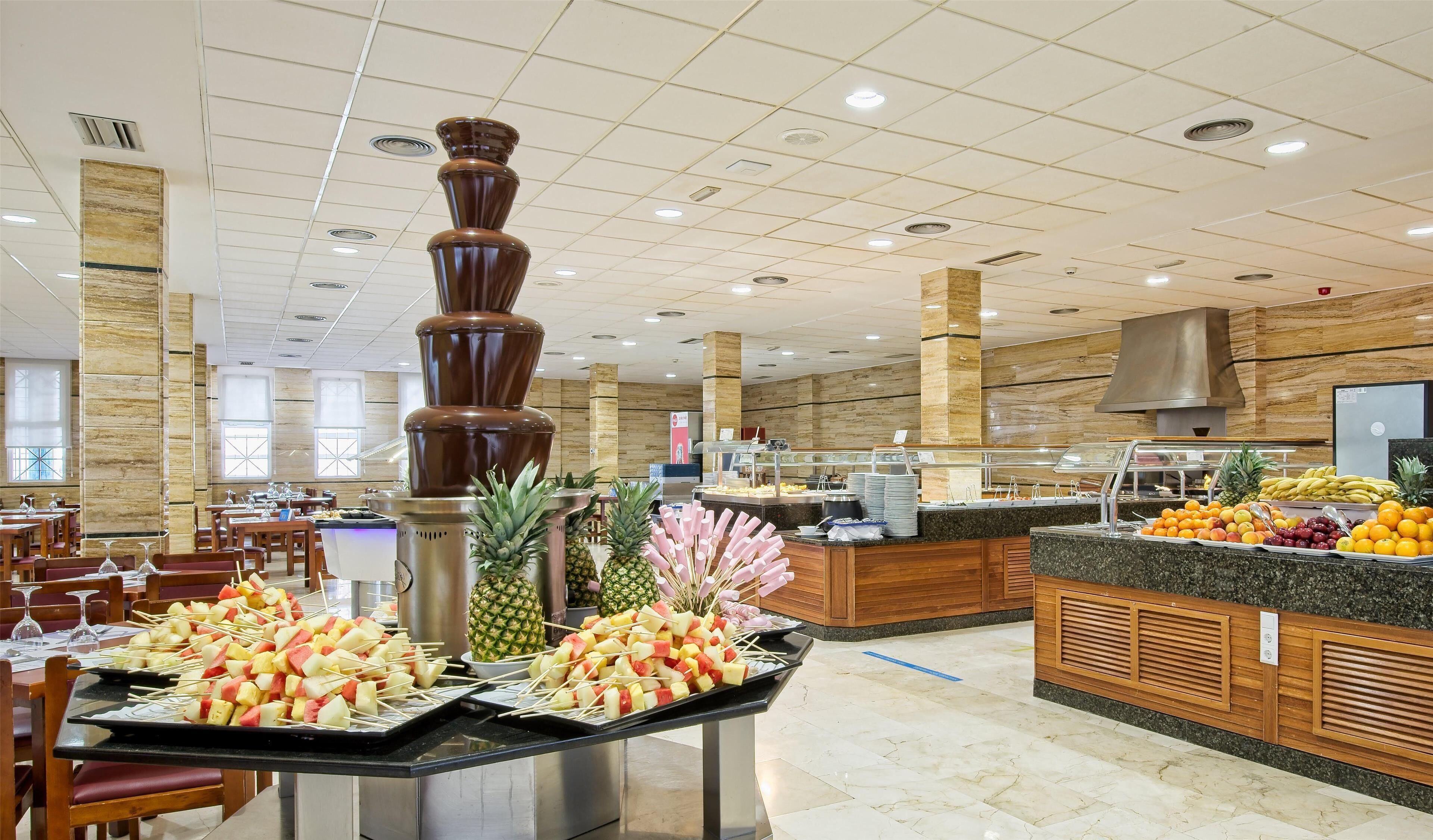 A buffet area with fruit skewers, a chocolate fountain, and a fruit display.