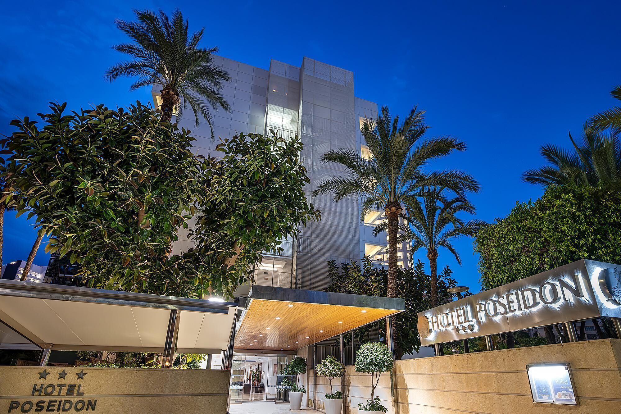 Un hotel moderno con un letrero llamativo, rodeado de exuberante vegetación y palmeras.