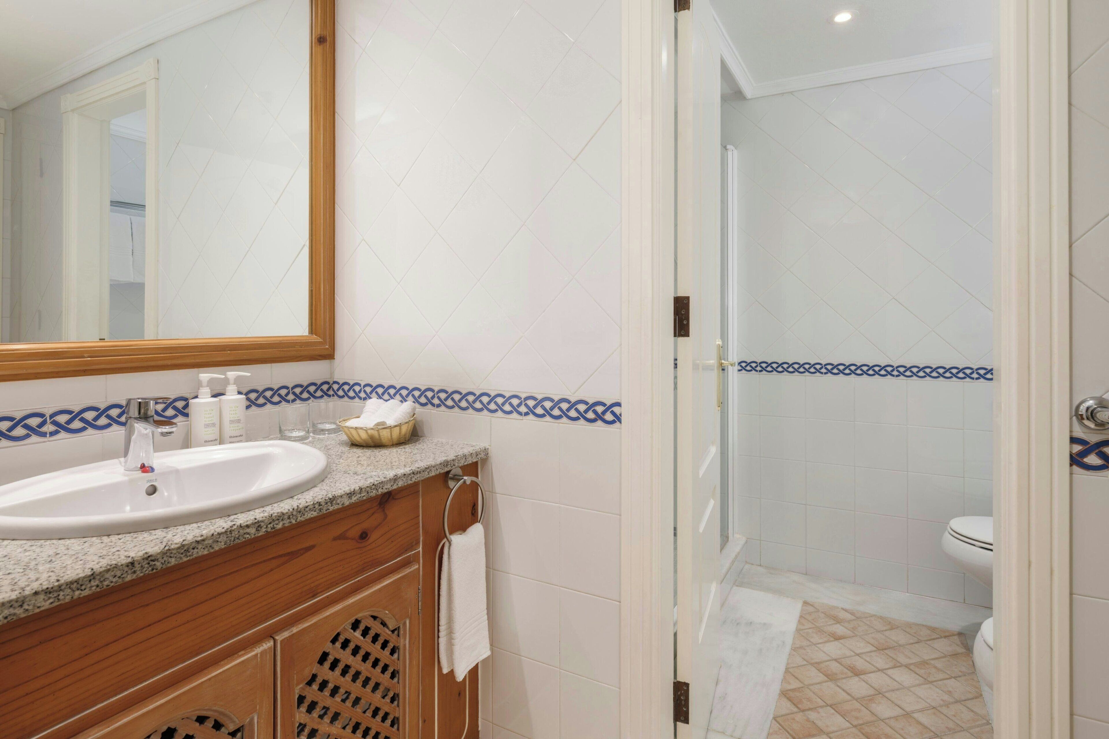 Une salle de bain avec un lavabo, un miroir et un espace douche.