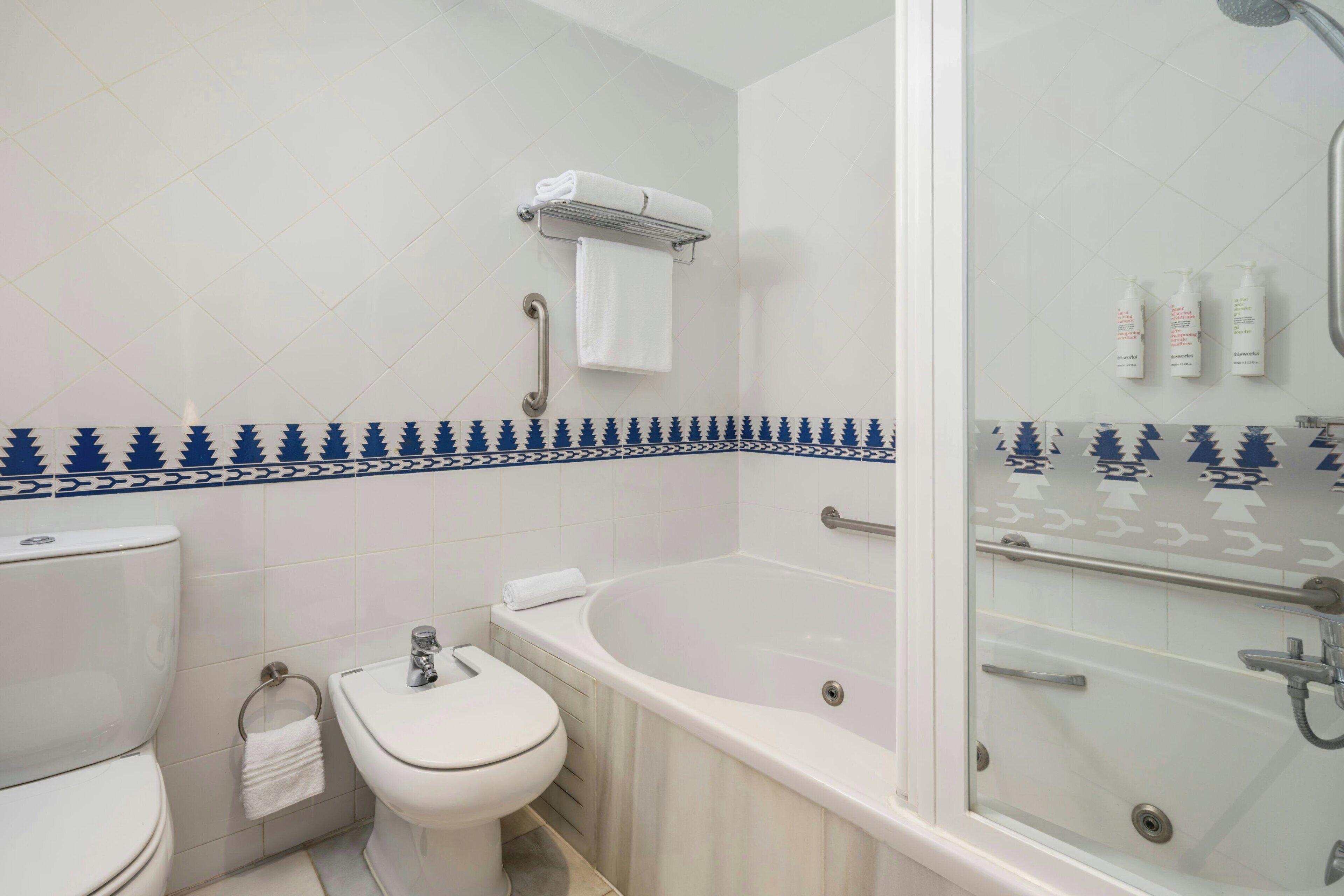 A bathroom with a toilet, bidet, bathtub, and shower.