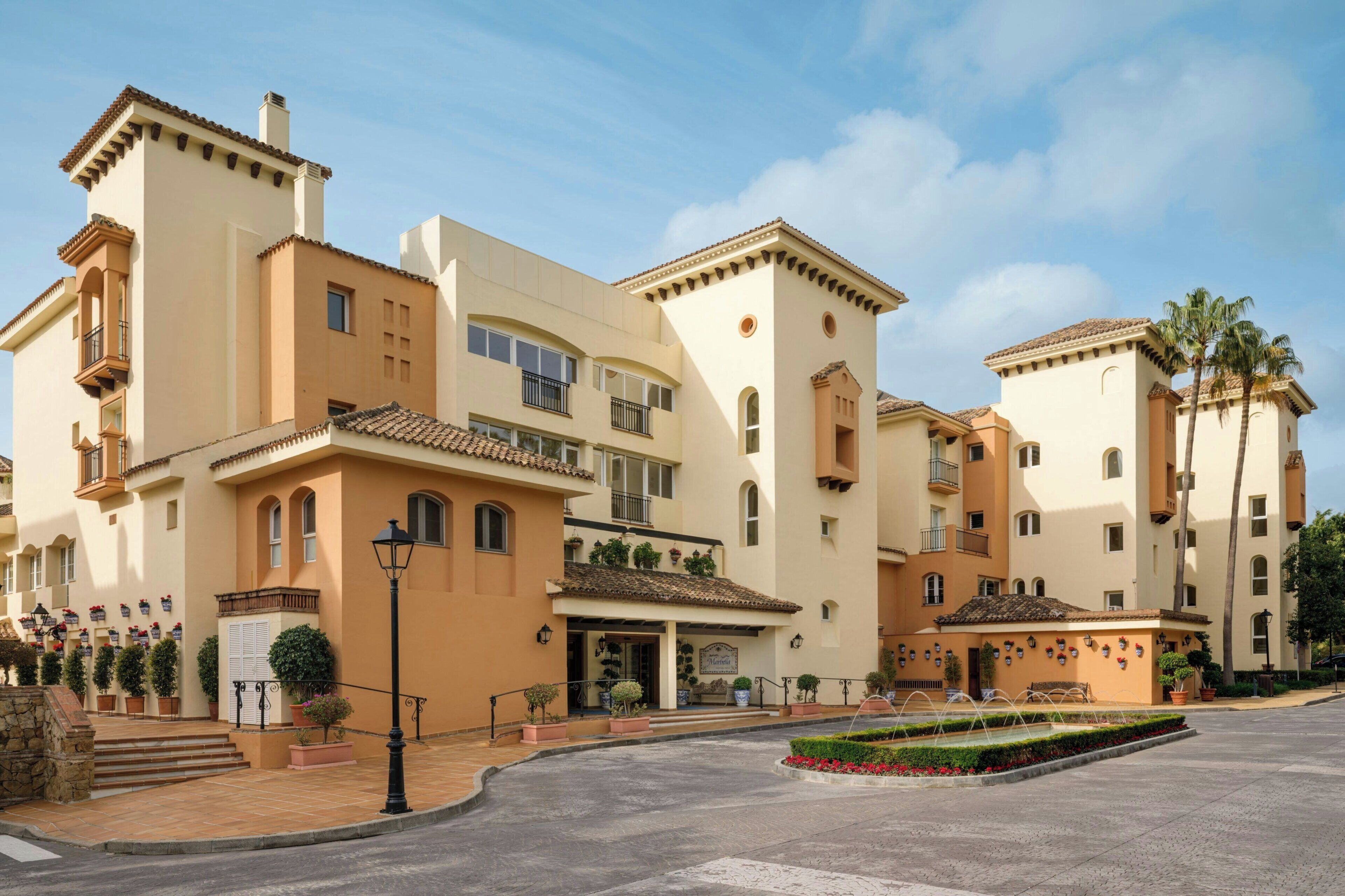 Un hotel de varios pisos con un patio central, balcones y un tejado de baldosas.