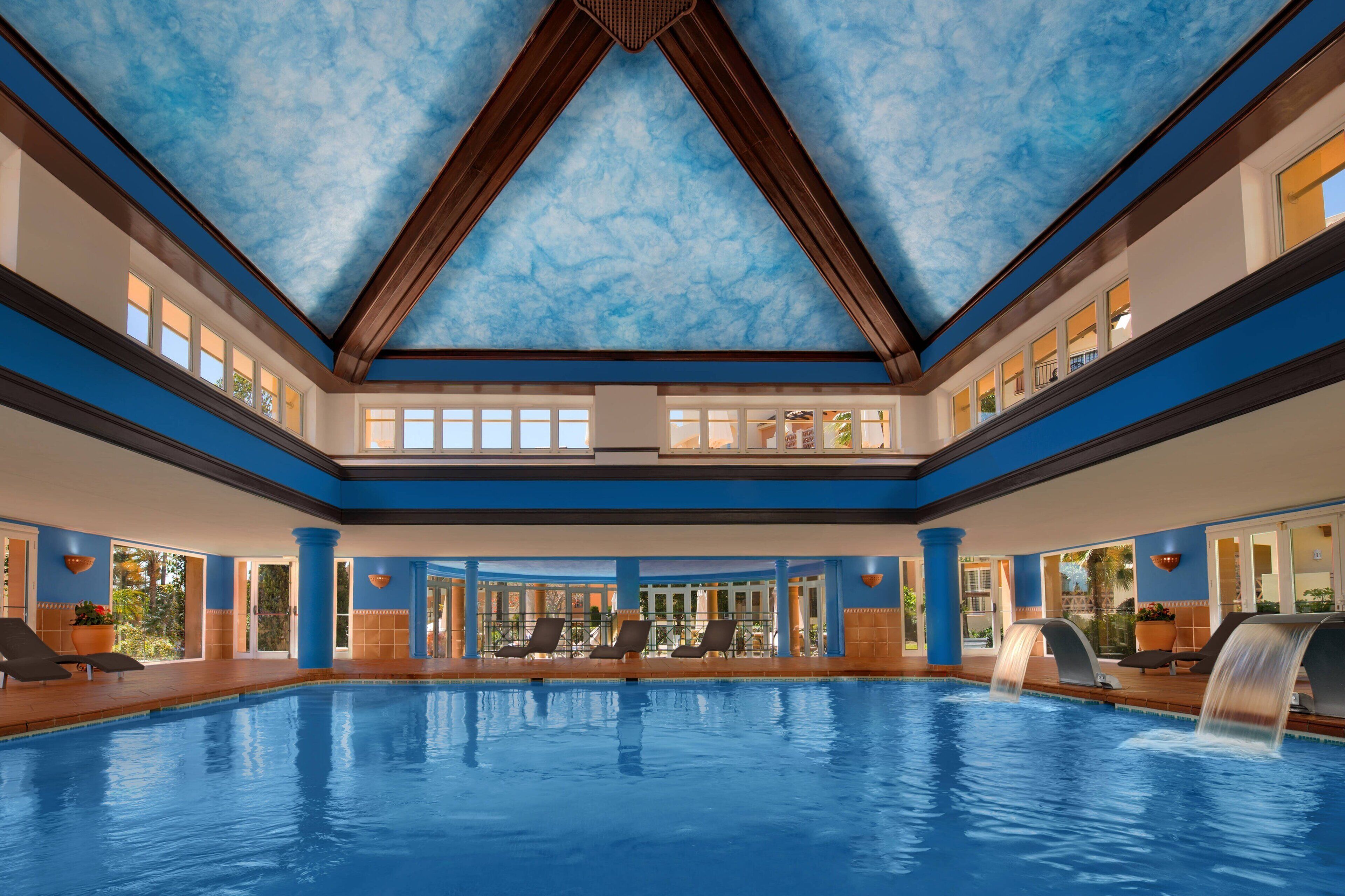 Una amplia piscina cubierta con techo azul y varios niveles de asientos.