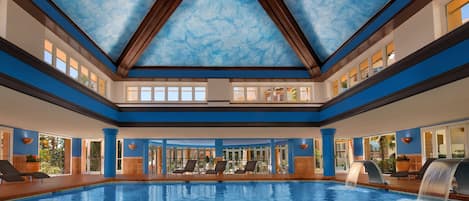 A large indoor swimming pool with a blue ceiling and multiple levels of seating.