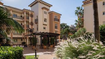 A courtyard with a pergola, palm trees, and potted plants.