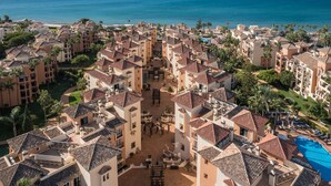 Un resort costero con varias edificaciones, un patio central y una zona de piscina.
