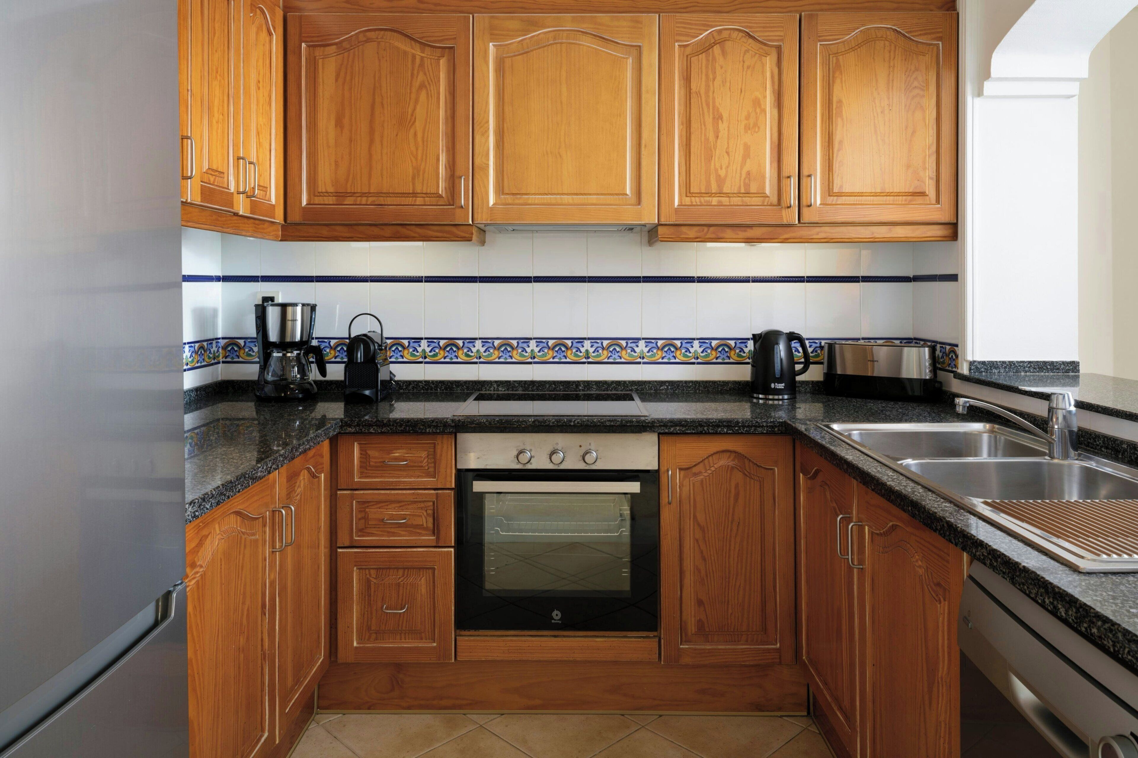 A kitchen with wooden cabinets, a built-in oven, a coffee maker, and a toaster.