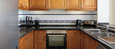 Una cocina con armarios de madera, horno empotrado, cafetera y tostadora.