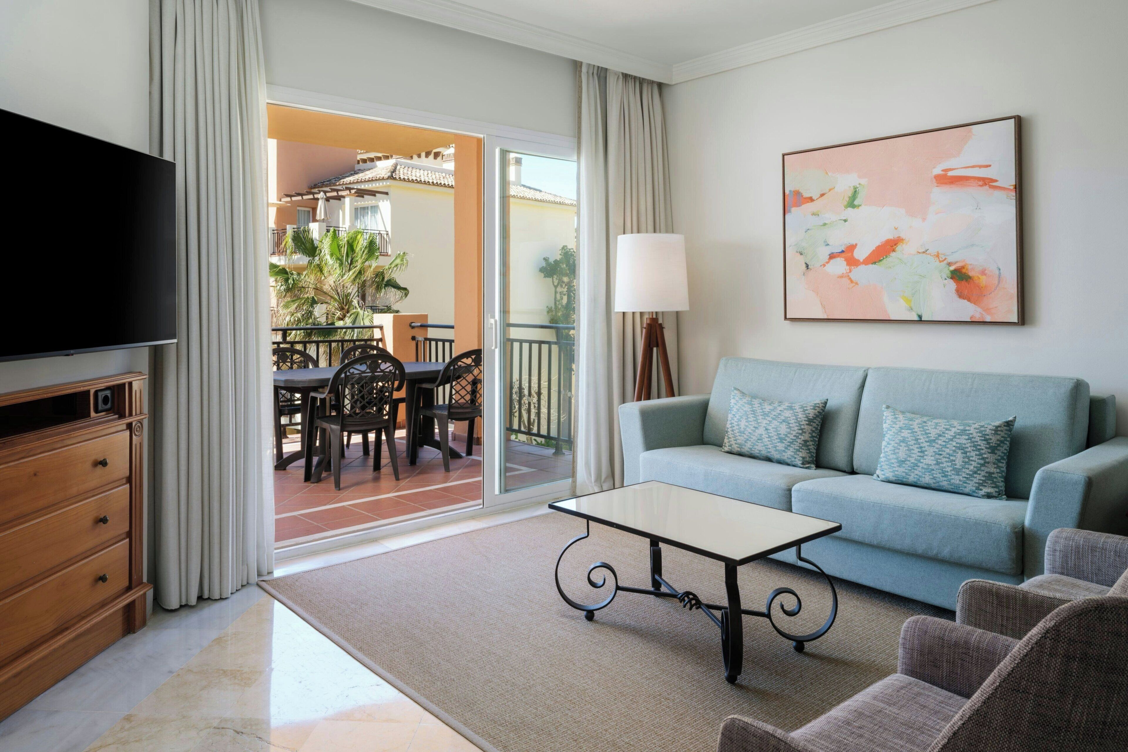 A living room with a TV, sofa, coffee table, and a painting on the wall.
