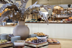 Disposição de buffet com diversos alimentos e um arranjo de planta decorativa.