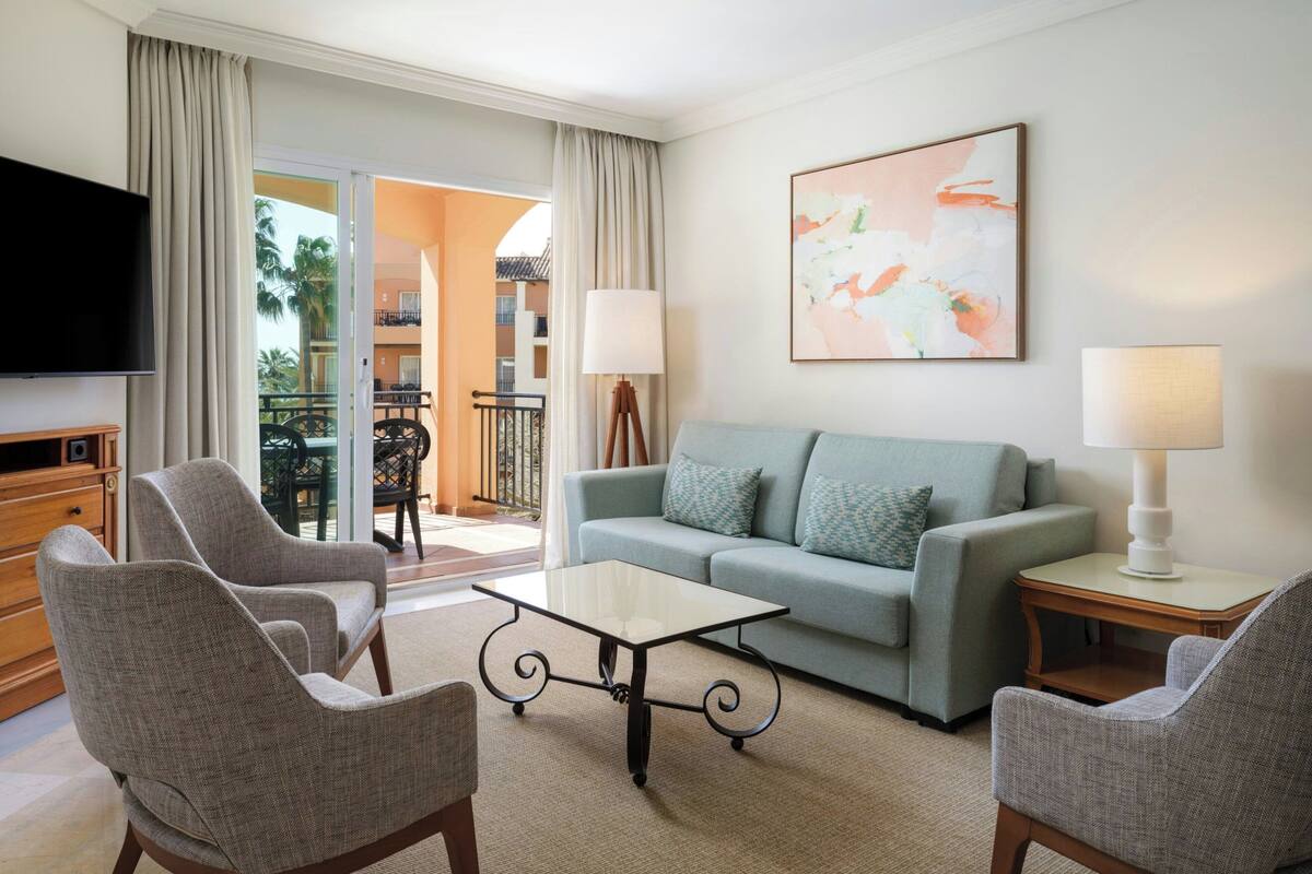 A living room with a sofa, two armchairs, a coffee table, and a TV.