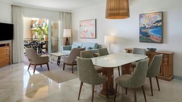 Un soggiorno moderno con tavolo da pranzo, sedie, divano, televisore e opere d'arte alle pareti.