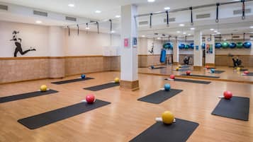 Ein Fitnessstudio mit Trainingsmatten, Bällen und einer Spiegelwand.